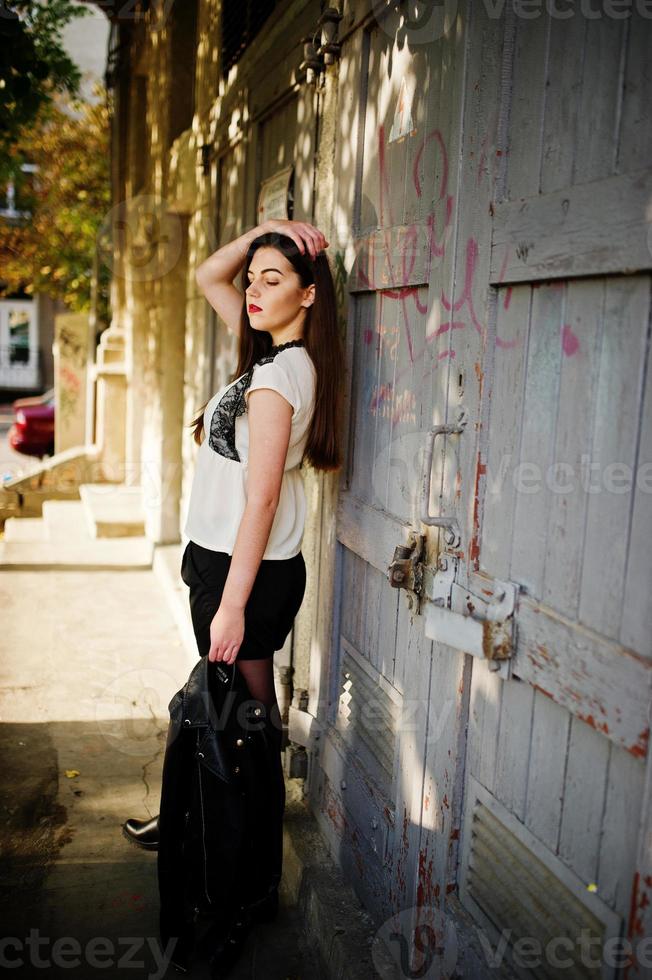 Stylish brunette girl wear on leather jacket and shorts posing at street. photo