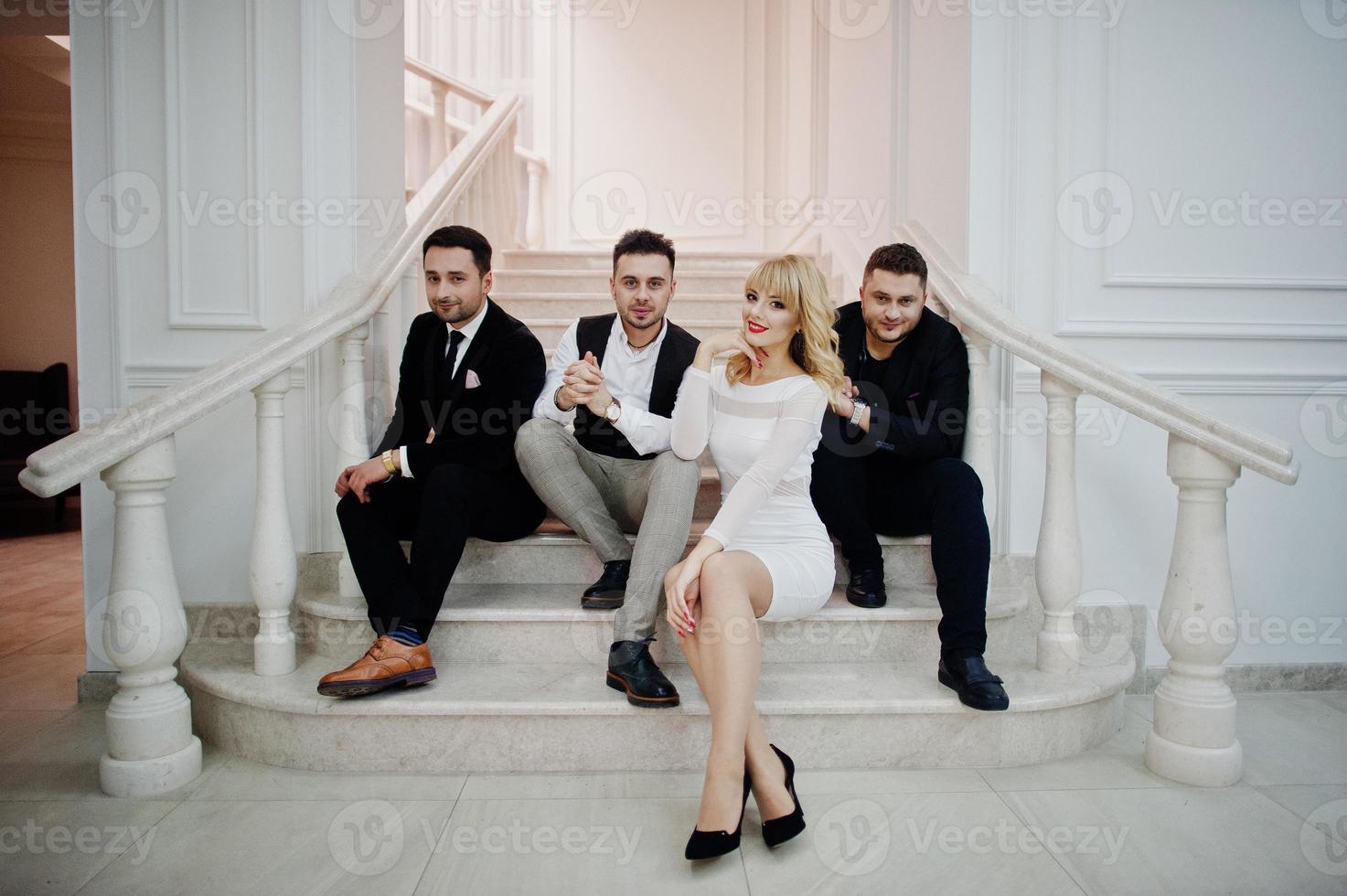 Three stylish bearded man well dressed with one blonde girl in white dress posed. Musician band or singers. photo