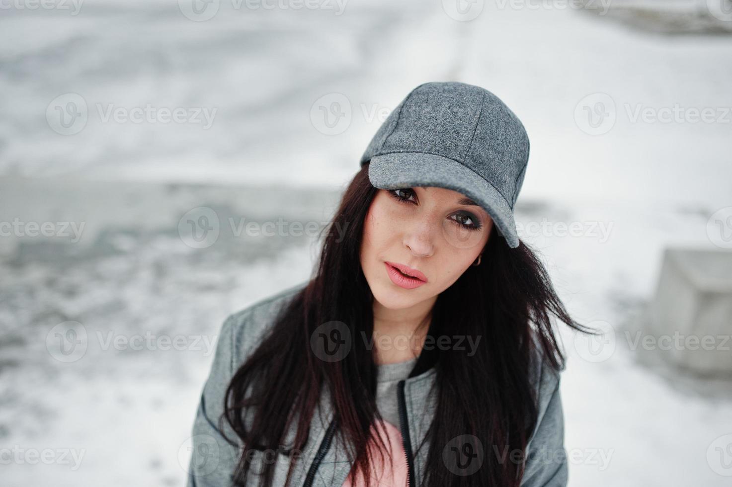 chica morena elegante con gorra gris, estilo casual de calle en el día de invierno. foto