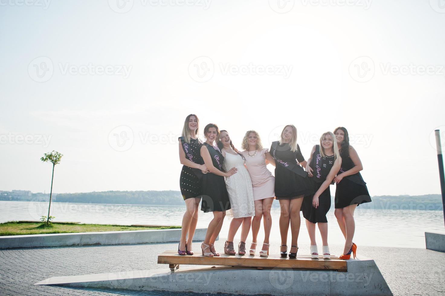 Group of 7 girls wear on black and 2 brides at hen party. photo