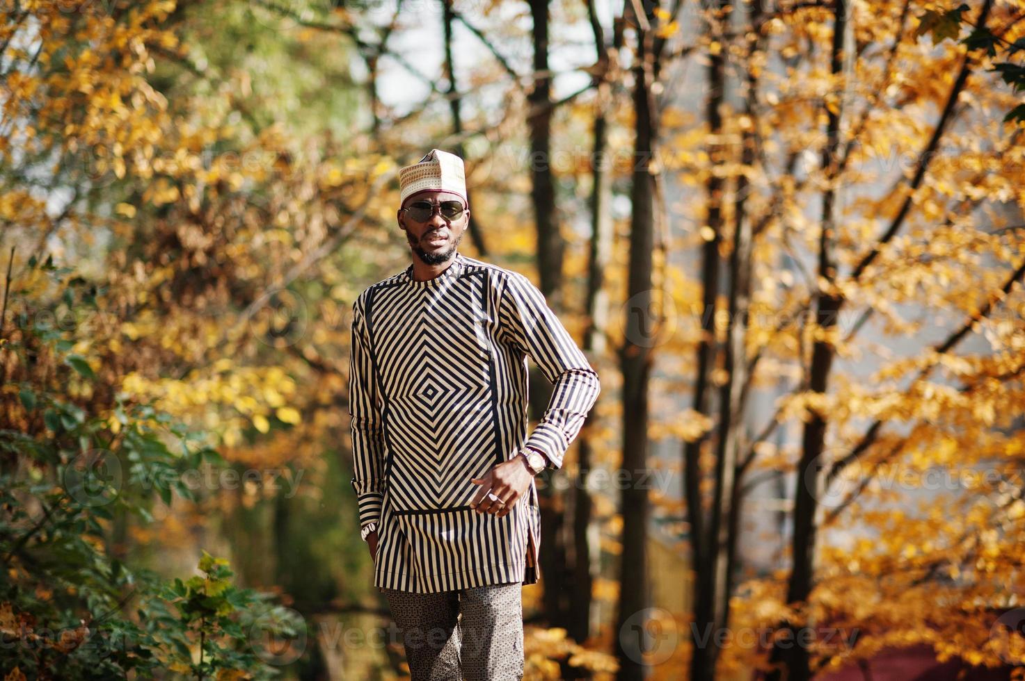 Portrait of stylish black african american man at hat and sunglasses against sunny autumn fall background. photo