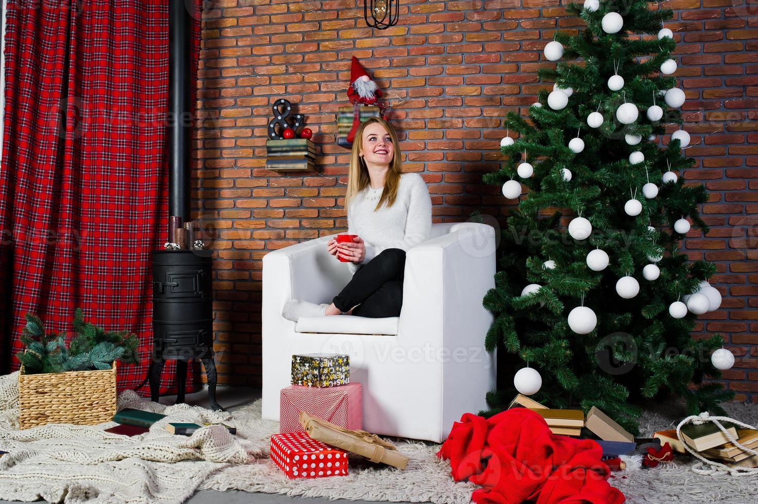 Cute girl wear on warm sweaters, black pants against new year tree with christmas decoration at studio. photo