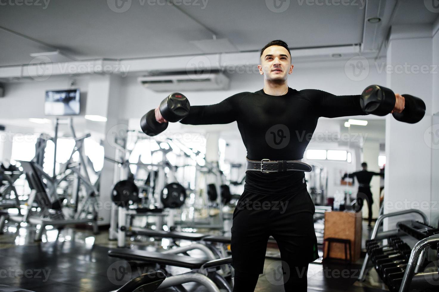 Muscular arab man training with dumbbells in modern gym. photo