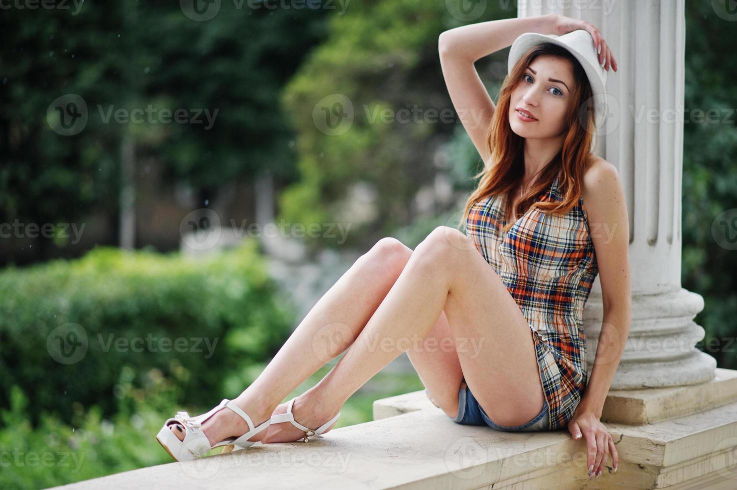 Amazing long legs with hig heels girl wear on hat sitting near vintage building columns. photo