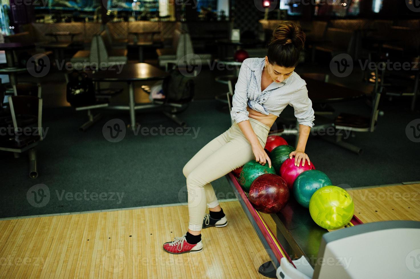 Girl with bowling ball on alley played at bowling club. photo