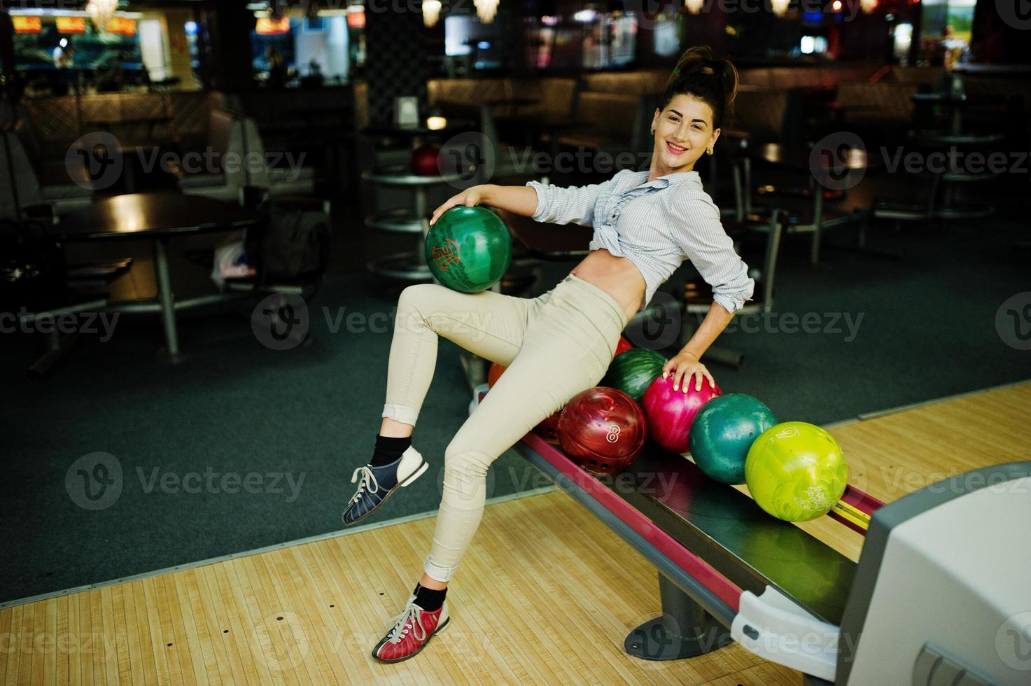 Girl with bowling ball on alley played at bowling club. photo