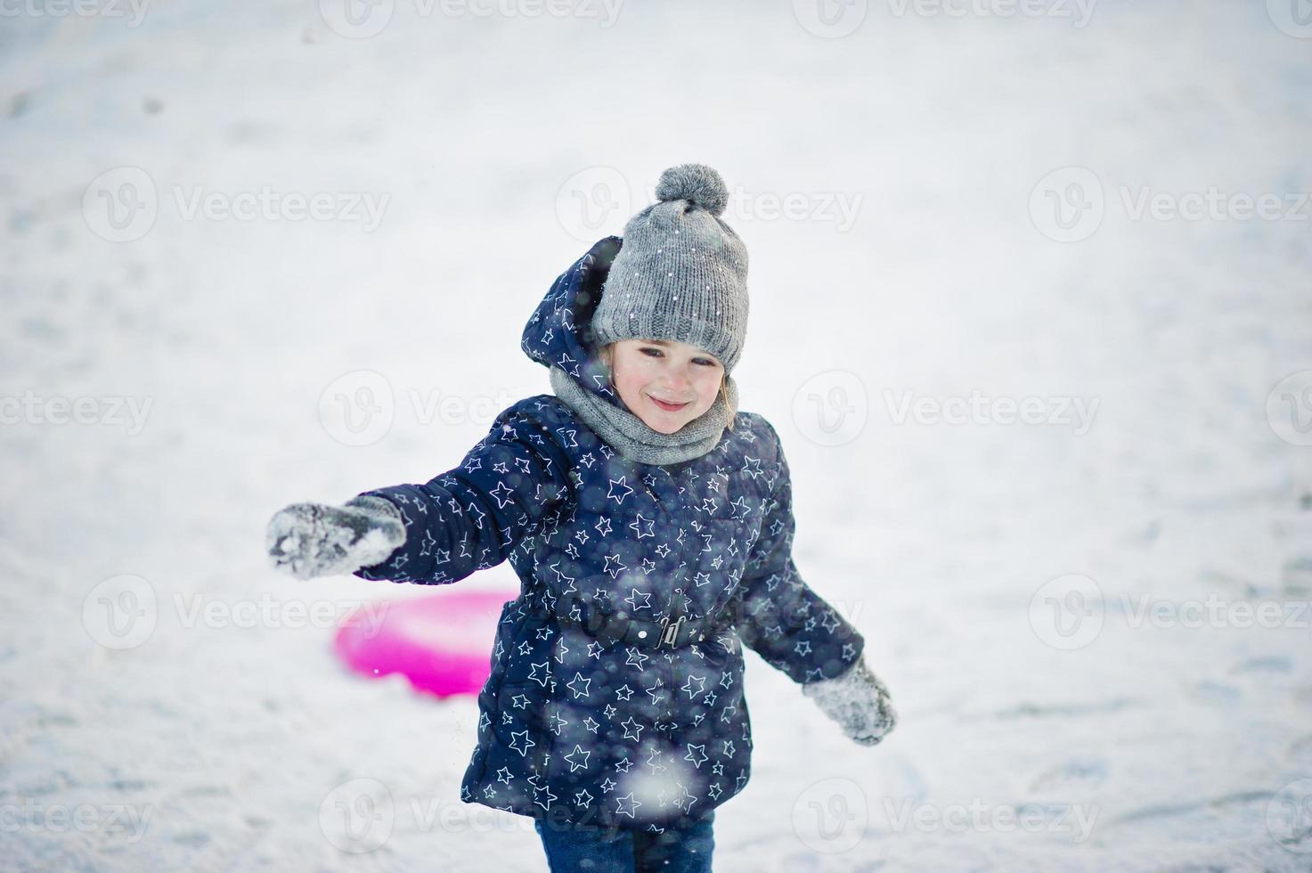 linda niña con trineos de platillos al aire libre en el día de invierno. foto