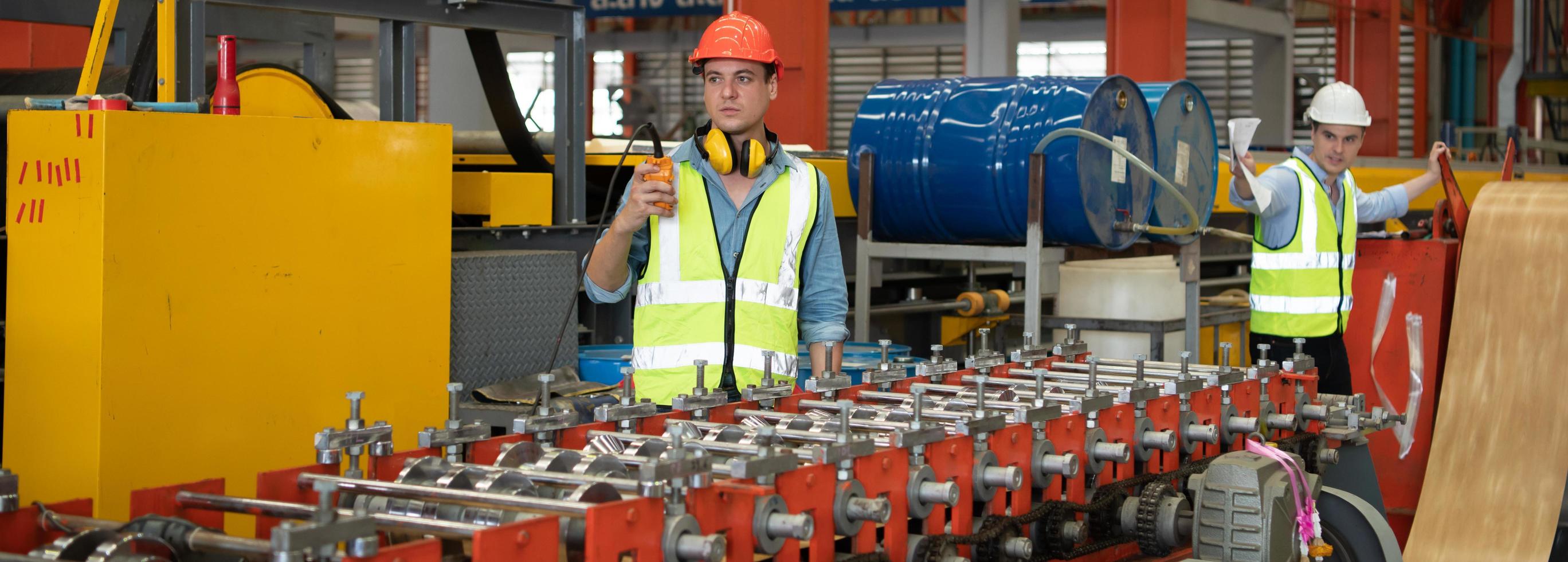 Two young engineers Testing and verifying the operation of the machines forming metal sheet tiles photo