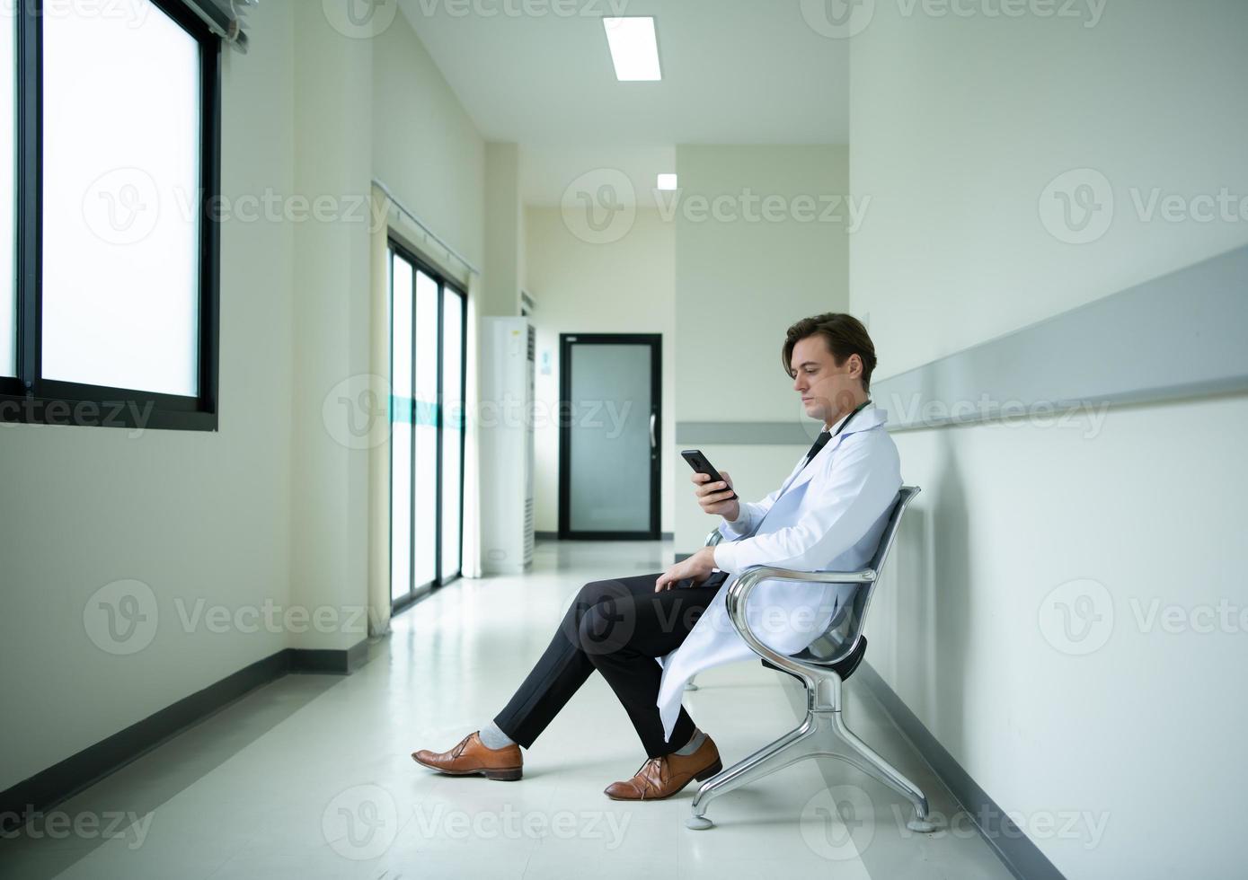 The doctor is using the phone to see the tasks that will be responsible for the day photo