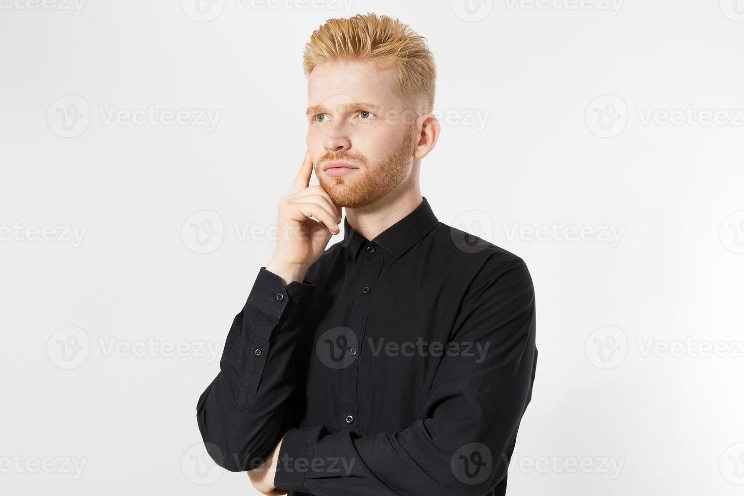 Hombre pensando, hombre de pelo rojo serio pensamiento pensativo retrato en estudio aislado sobre fondo blanco, joven atractivo en camisa negra foto
