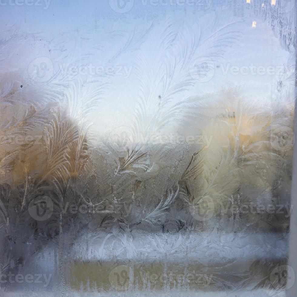 View of the old city house from a frozen winter window. Texture ice patterns on glass. Selective focus. photo