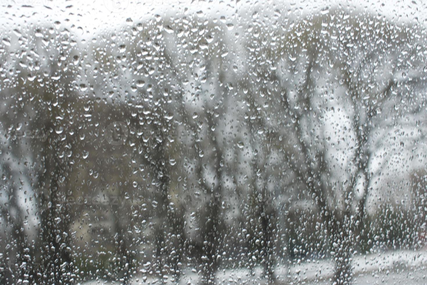 texture of bokeh drops on glass in front of urban park landscape photo