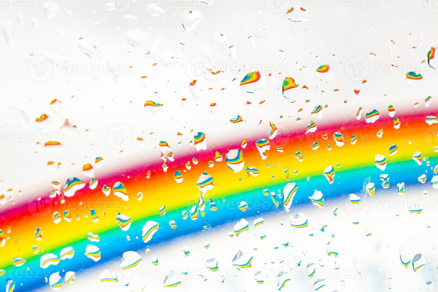 A rainbow behind a glass windows with water drops, Point of view, from behind the glass with drops. photo