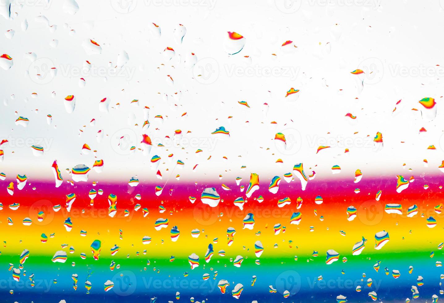 A rainbow behind a glass windows with water drops, Point of view, from behind the glass with drops. photo