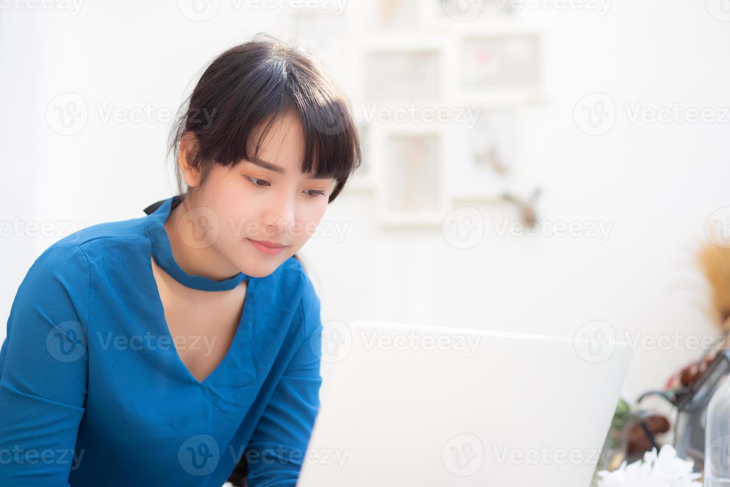 Beautiful portrait asia young woman working online on laptop sitting at cafe shop, professional female freelance using notebook computer, business and communication concept. photo
