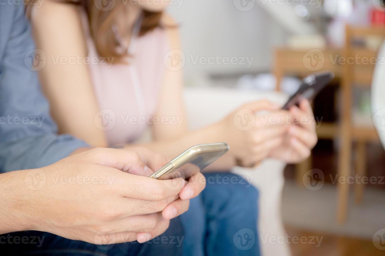 Closeup hand asian couple sitting on sofa with problem about relationship because addicts social network media together, asia family expression with looking phone with ignoring and indifferent. photo