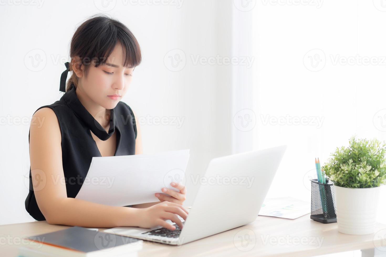 Young asian woman working and typing with laptop computer at office, businesswoman looking graph diagram analysis statistic data of finance, girl using notebook, profit growth, business concept. photo