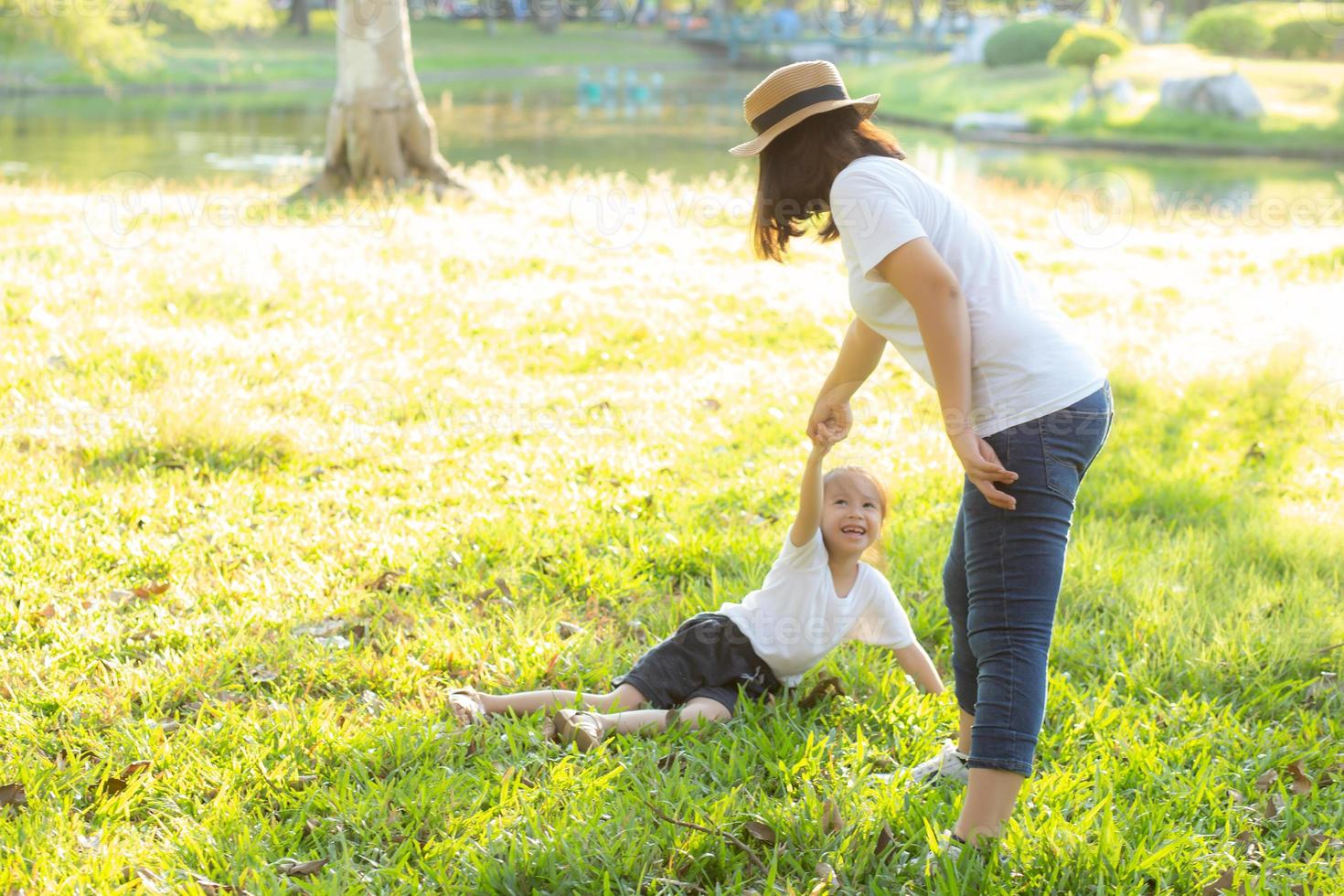 Young asian mother and little daughter playing the park with fun and happiness, family enjoy and relax and leisure together, mom and children smiling laughing in summer day. photo