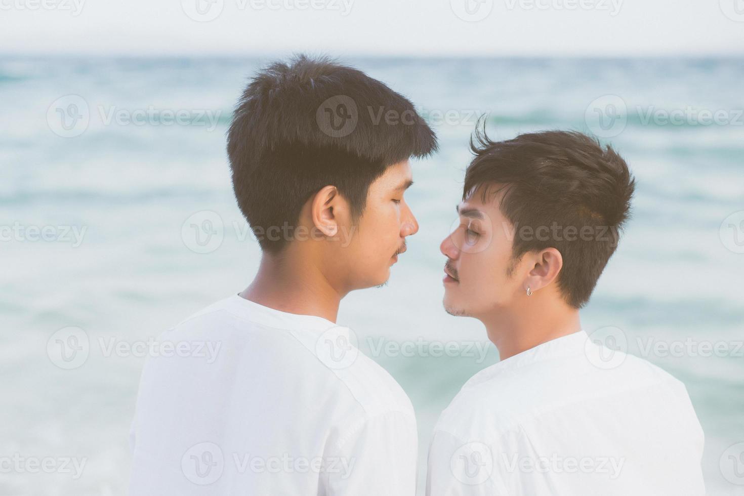 vista posterior joven pareja asiática de pie juntos en la playa en verano, asia gay tomados de la mano yendo al mar por placer y relajarse con romántico y feliz en vacaciones en el mar, lgbt con concepto legal. foto