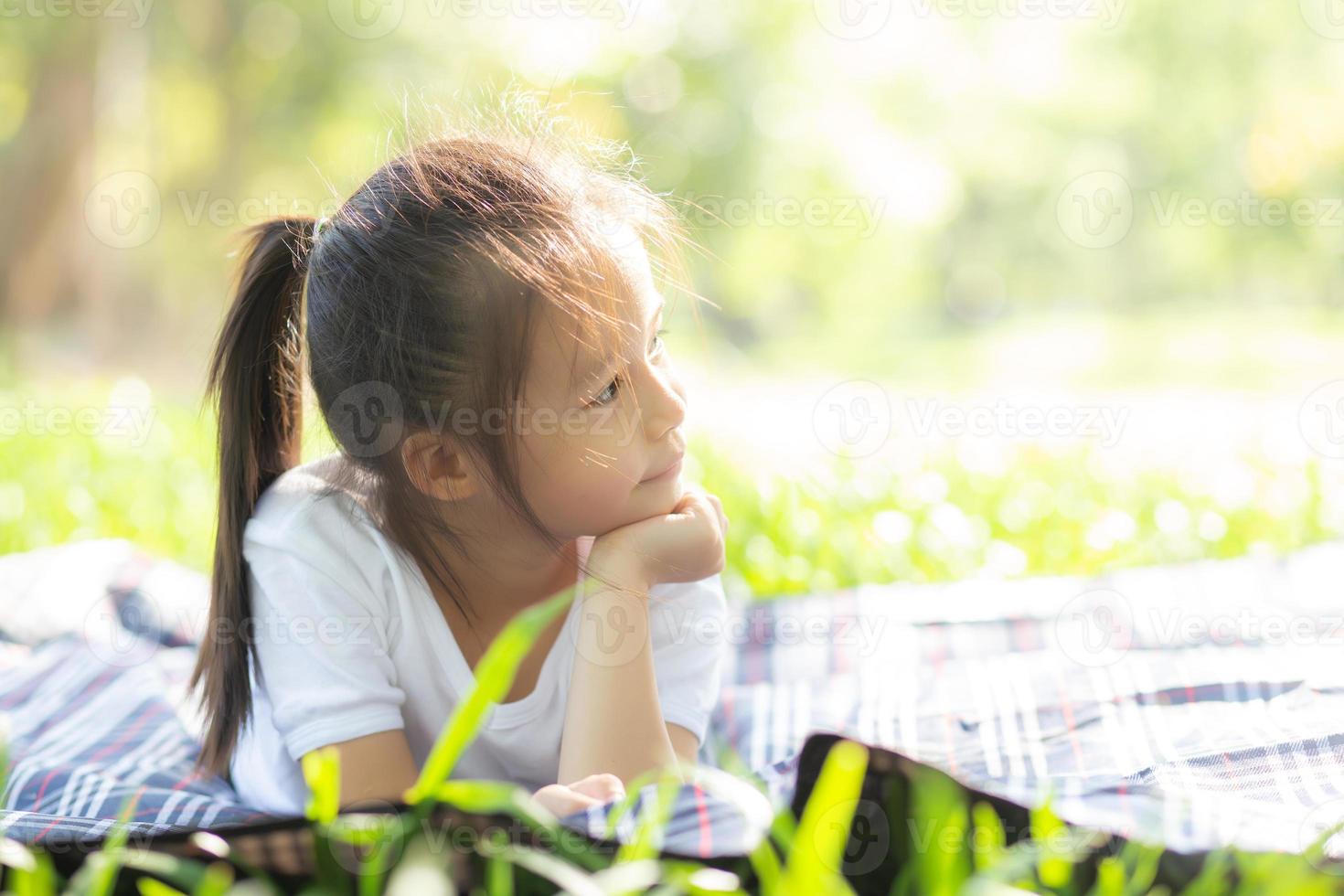 cara de retrato de linda niña asiática y felicidad y diversión infantil en el parque en verano, sonrisa y felicidad de niño asiático y relajación en el jardín, concepto de infancia de estilo de vida. foto