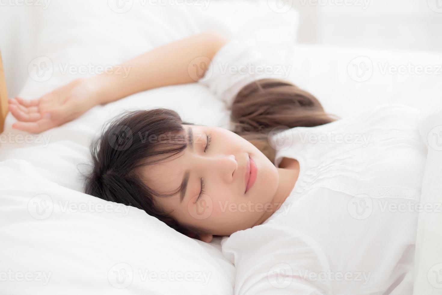 bella joven asiática durmiendo en la cama con la cabeza en la almohada cómoda y feliz. chica con relax por concepto de salud. foto