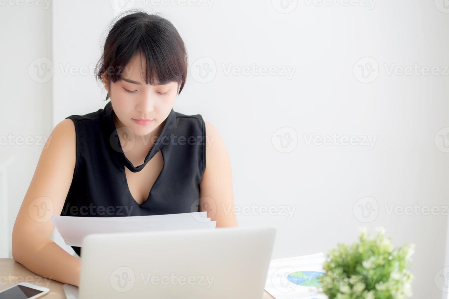 Young asian woman working and typing with laptop computer at office, businesswoman looking graph diagram analysis statistic data of finance, girl using notebook, profit growth, business concept. photo