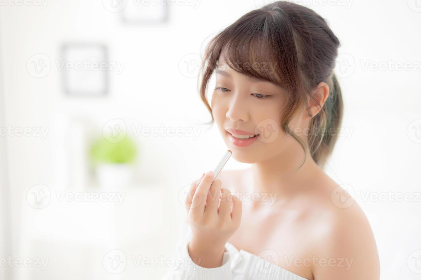 hermoso retrato joven mujer asiática aplicando lápiz labial de maquillaje en la habitación, labios de belleza maquillaje de niña de asia y moda cosmética en la boca en casa, estilo de vida y concepto de atención médica. foto