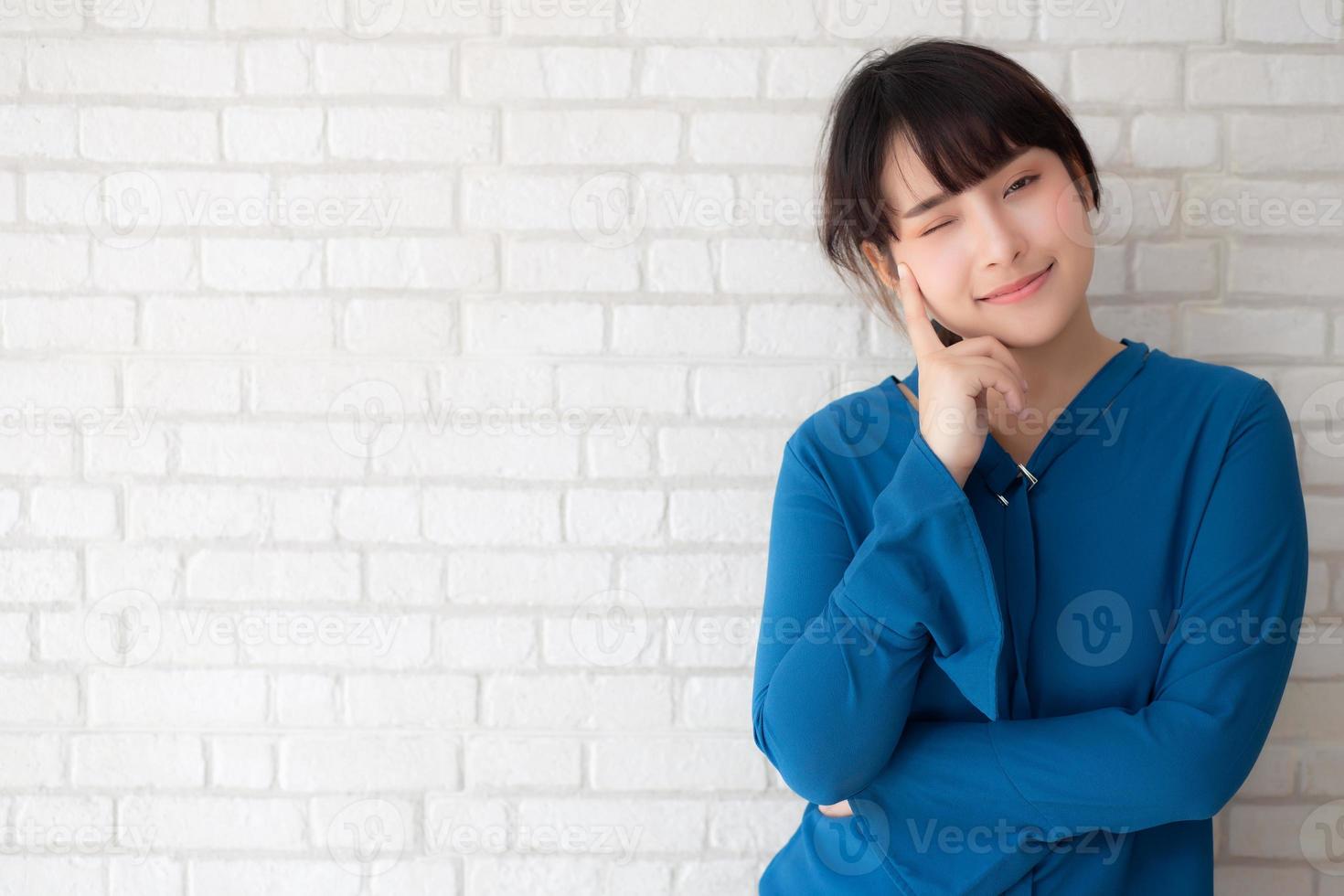 hermoso retrato joven asiática sonriente y confiada pensando con cemento y antecedentes de hormigón, niña de pie expresión seria o dudas con idea e inspiración, concepto de estilo de vida. foto