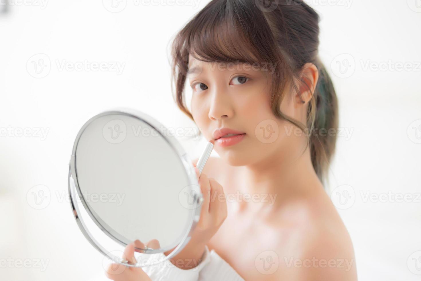 Beautiful portrait young asian woman looking mirror applying makeup lipstick at room, beauty lips asia girl makeup and cosmetic fashion on mouth at home, lifestyle and health care concept. photo