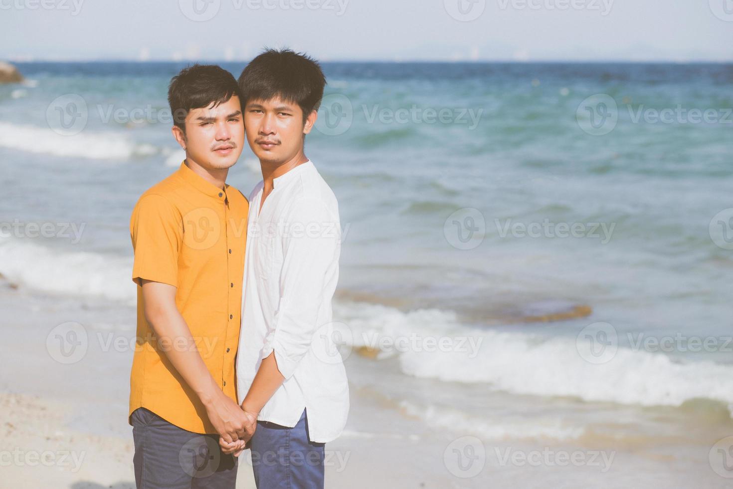 Homosexual portrait young asian couple standing together on beach in summer, asia gay holding hands going sea for leisure and relax with romantic and happy in vacation at sea, LGBT with legal concept. photo