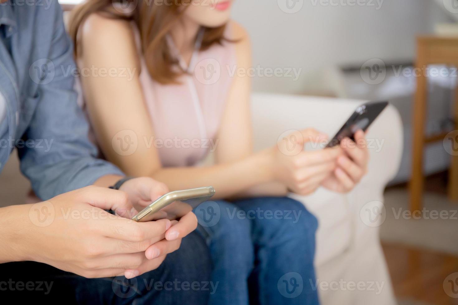 Closeup hand asian couple sitting on sofa with problem about relationship because addicts social network media together, asia family expression with looking phone with ignoring and indifferent. photo