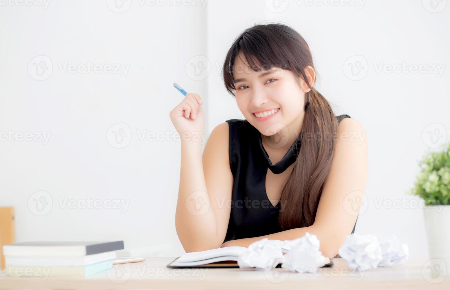 Beautiful asian woman writer smiling thinking idea writing on notebook diary with planning working on desk office, lifestyle asia girl have inspiration with success, education and business concept. photo