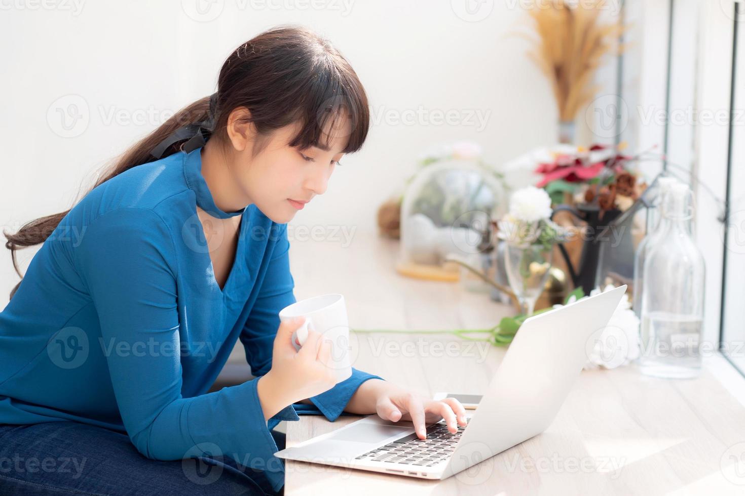 hermosa joven mujer asiática independiente sonriendo trabajando y en una computadora portátil en la cafetería de escritorio con una chica asiática profesional que usa un cuaderno y bebe café, concepto de negocios y estilo de vida. foto