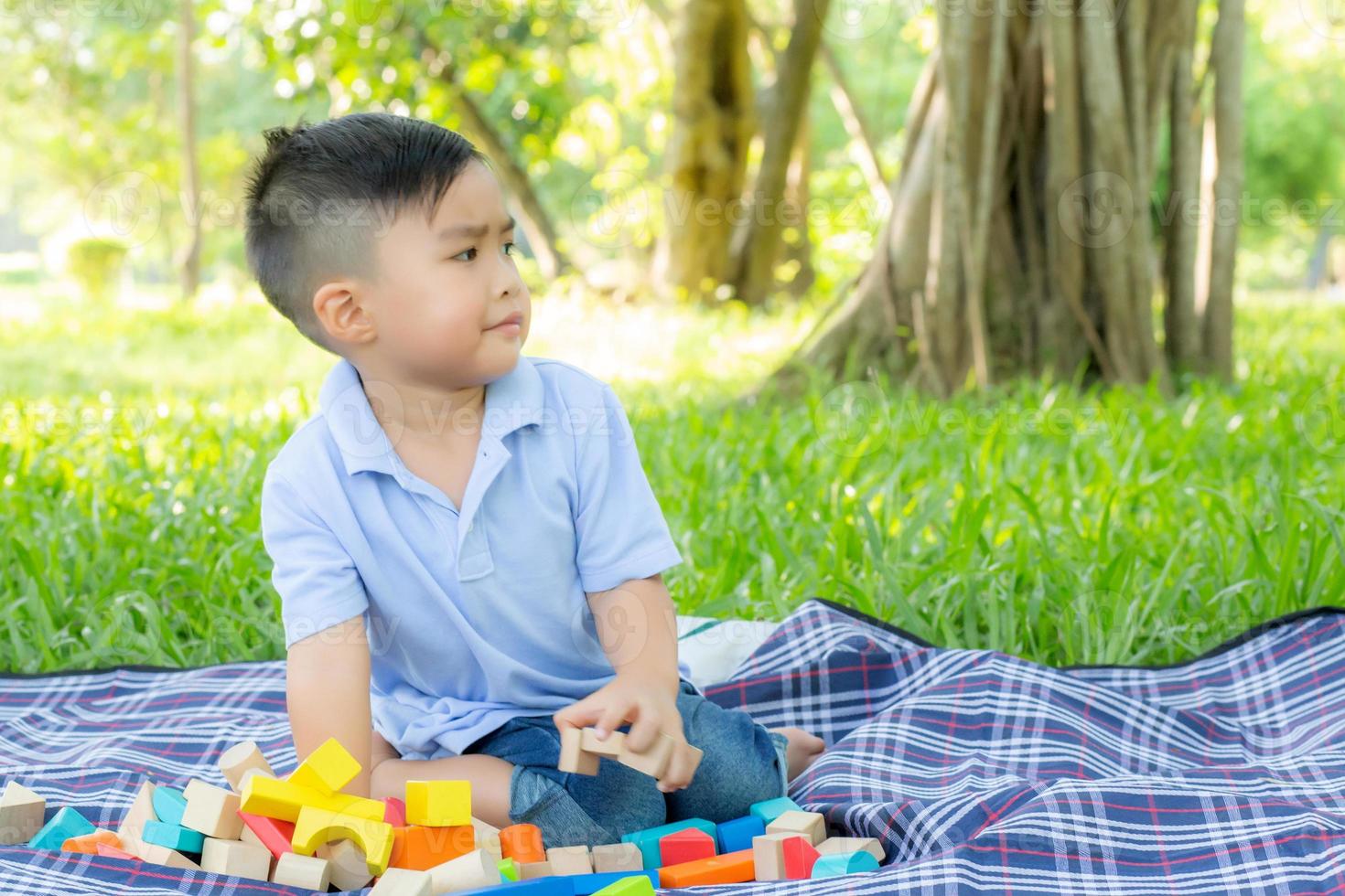 el niño pequeño está jugando por la idea y la inspiración con un bloque de juguete en el campo de hierba, un niño aprendiendo con un bloque de construcción para la educación, actividad infantil y juego en el parque con felicidad en el verano. foto