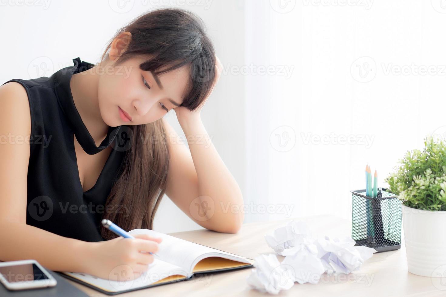 Beautiful asian woman tired and stressed with writing overworked at desk, girl with worried not idea with notebook and crumpled paper at office, freelance and business concept. photo