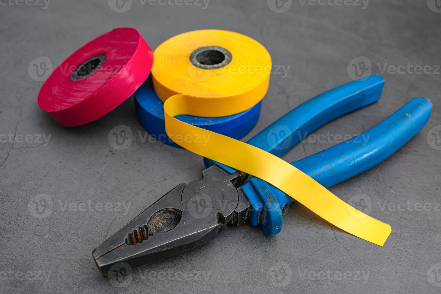 Three skeins of electrical tape in different colors and pliers photo