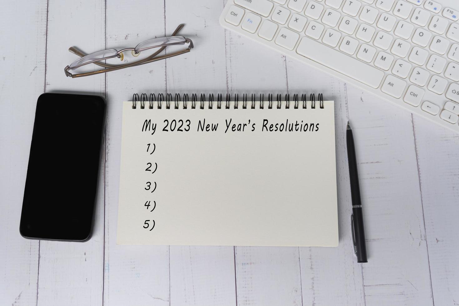 2023 New Year's Resolutions text on notepad on wooden desk. Copy space. photo