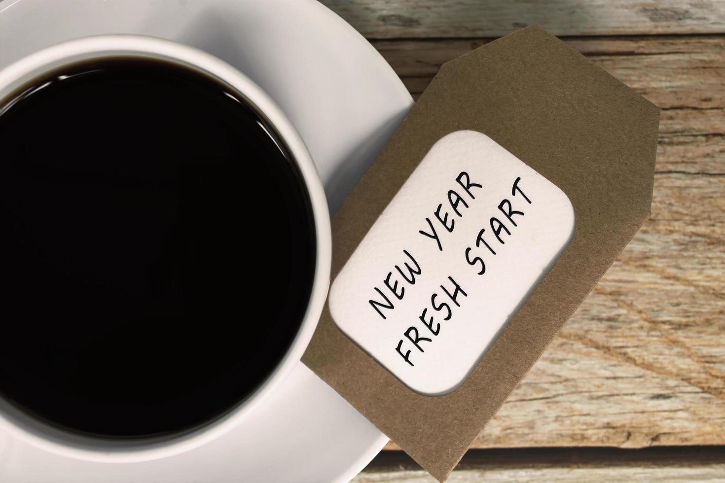 New year fresh start words on notepad with coffee cup on wooden desk. photo