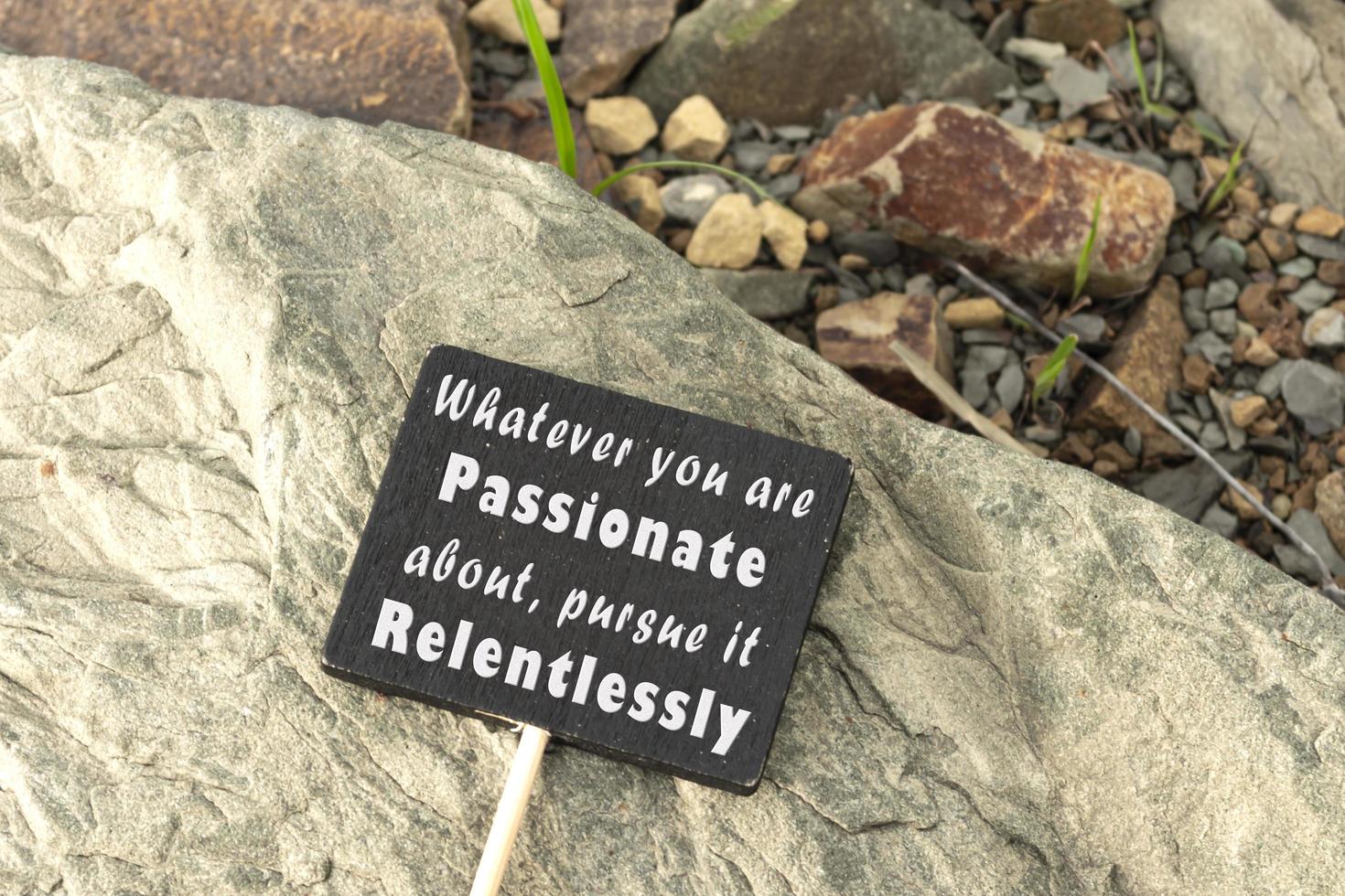 cita motivacional e inspiradora en pizarra sobre fondo de playa de piedra. foto