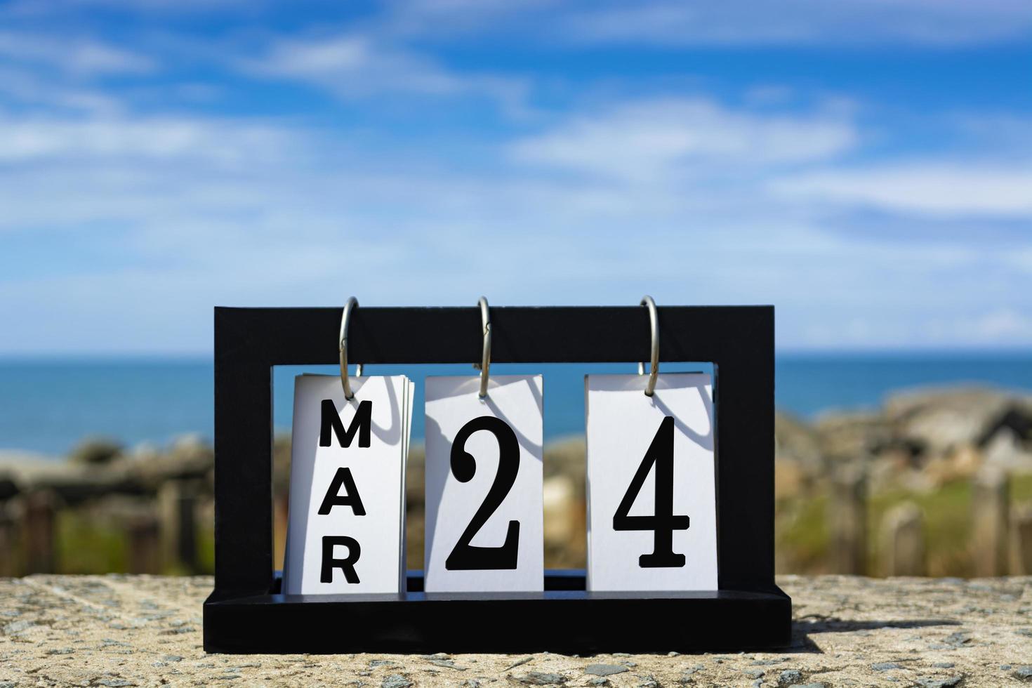 Mar 24 calendar date text on wooden frame with blurred background of ocean. photo