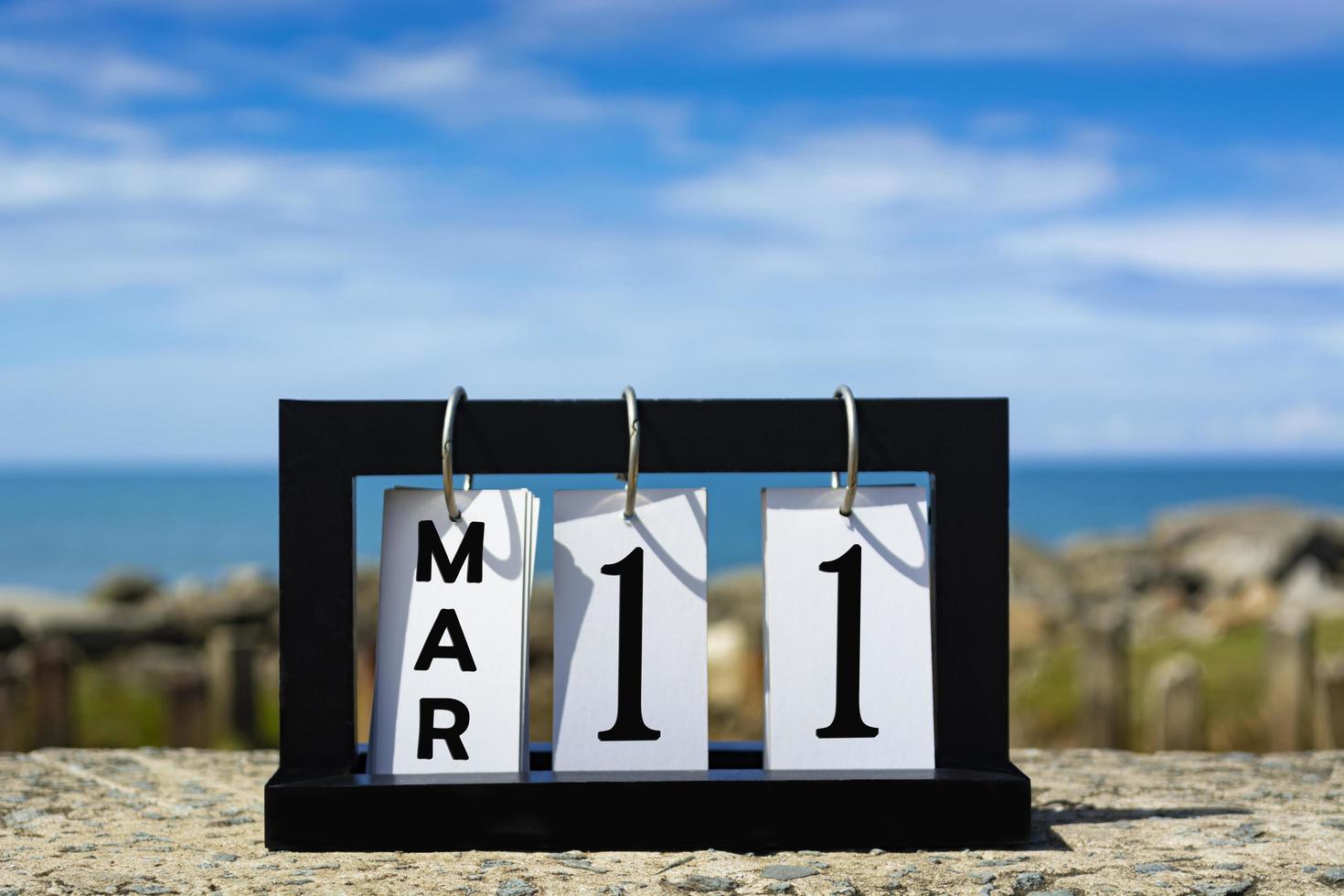 Mar 11 calendar date text on wooden frame with blurred background of ocean. photo