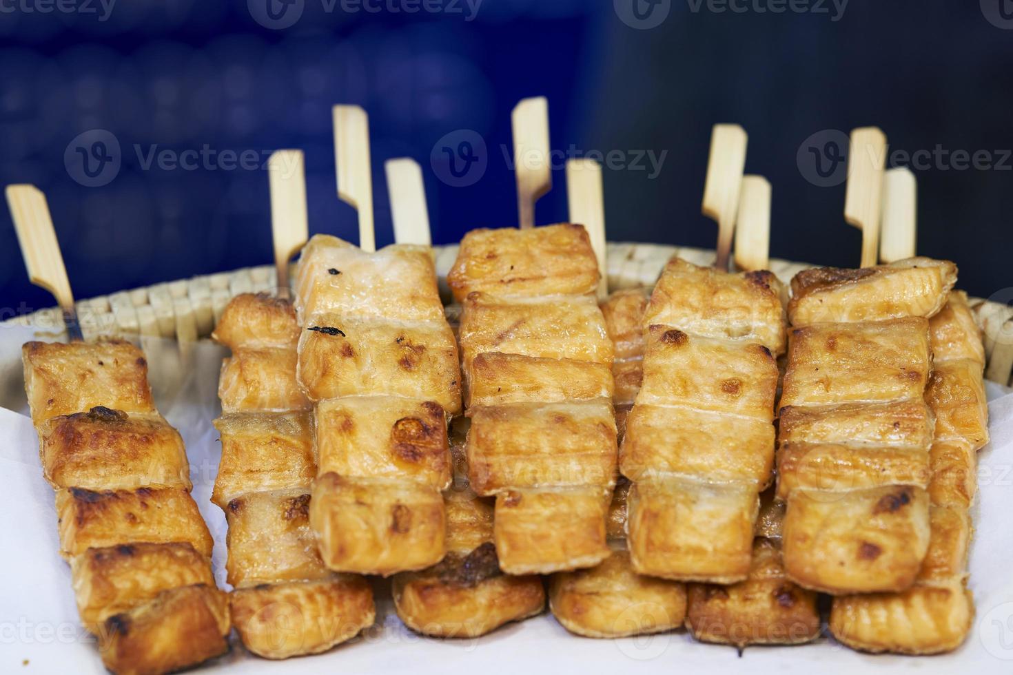 cerca de brochetas de salmón a la parrilla en palos de madera, mercado de comida callejera tailandesa foto