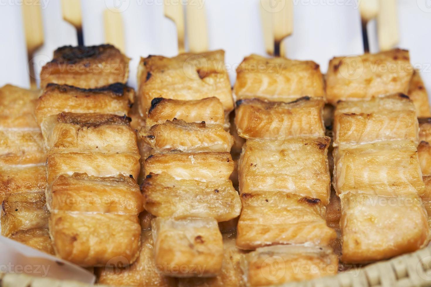 cerca de brochetas de salmón a la parrilla en palos de madera, mercado de comida callejera tailandesa foto