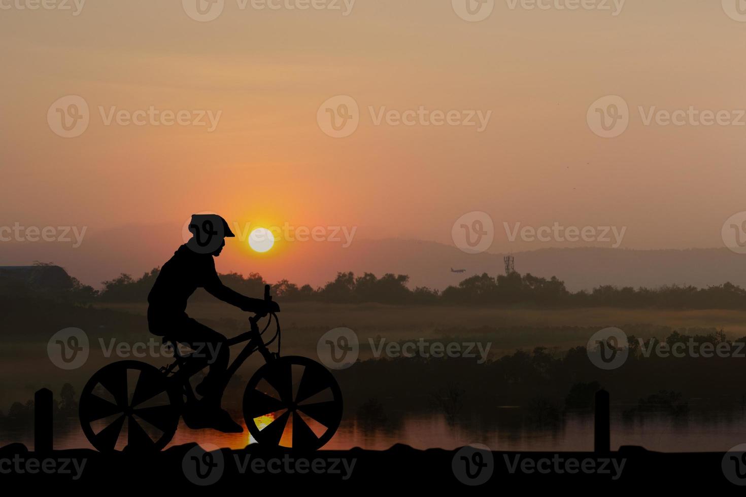 Silhouettes Man and bicycle on mountain in the sunlight photo