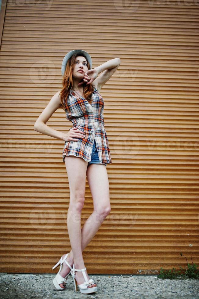 Amazing long legs with hig heels girl wear on hat against shutter. photo