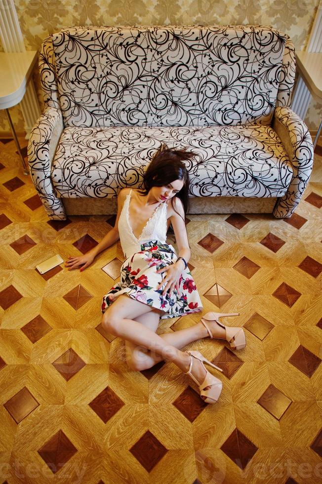 retrato de una mujer asombrosa con un hermoso vestido tendido en el suelo de madera. foto