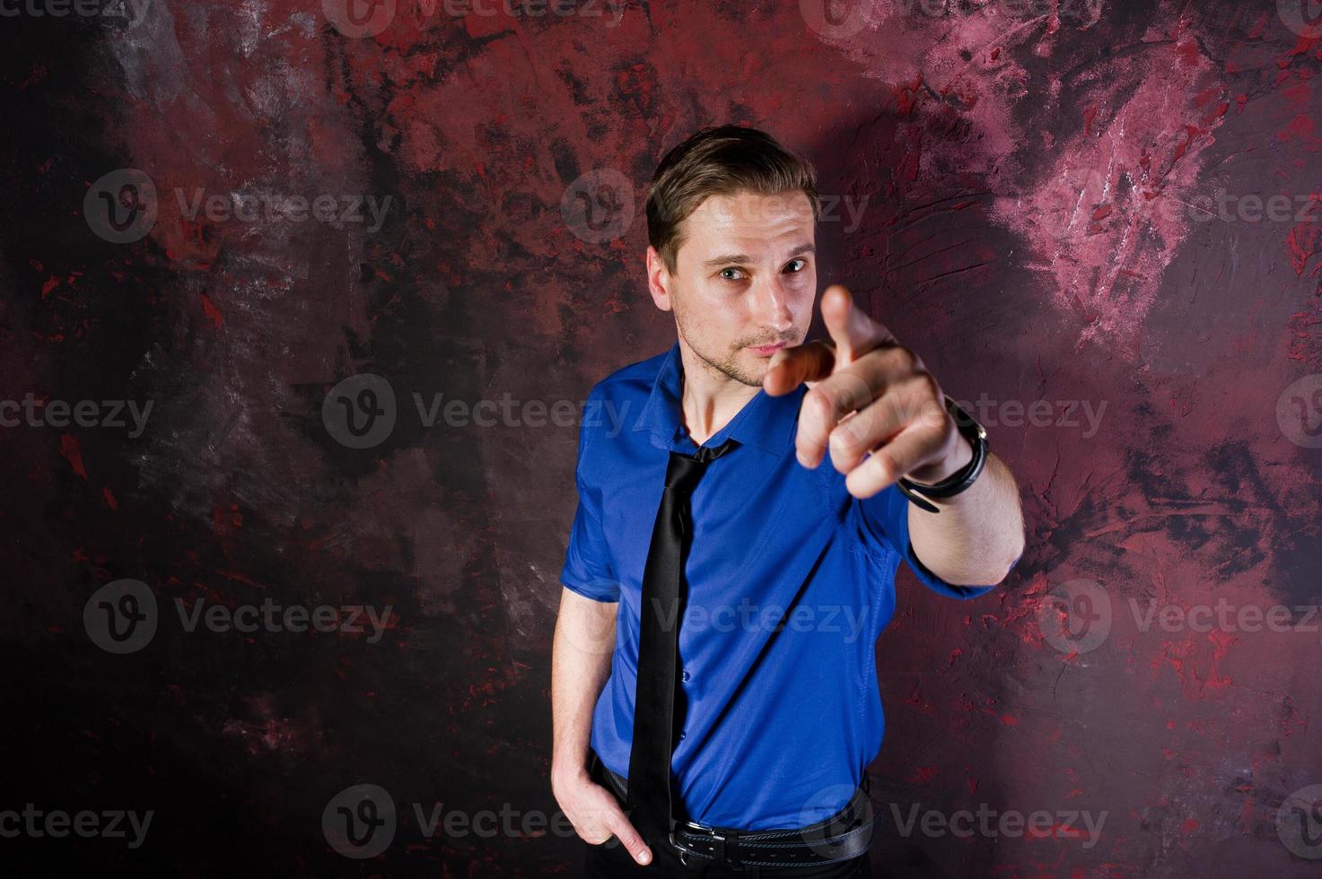 retrato de estudio de un hombre elegante, vestido con camisa azul y corbata, mostrando el dedo. foto