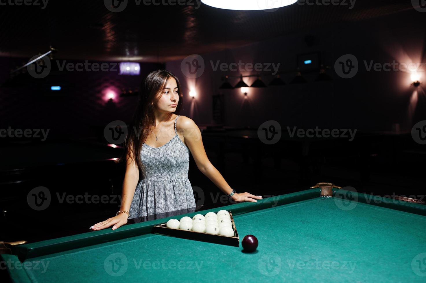 Portrait of a stunning woman standing next to the billiards table. photo