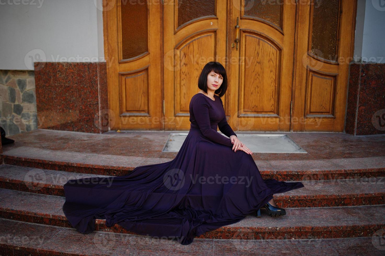 mujer morena adulta en el fondo del vestido violeta viejas puertas de madera. foto