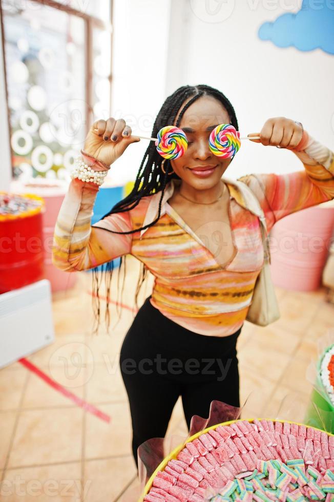 African american millennial lady at candy shop with lolipops. photo